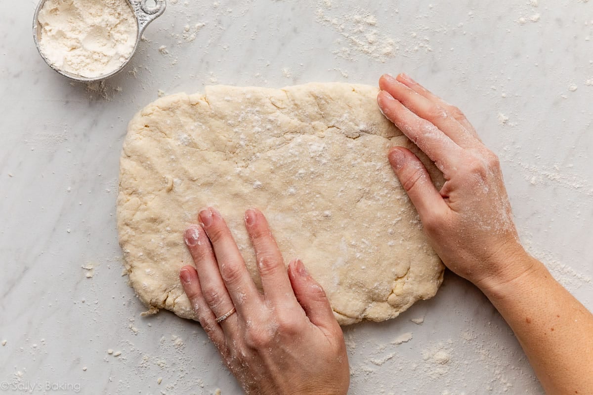 hands patting down biscuit dough.