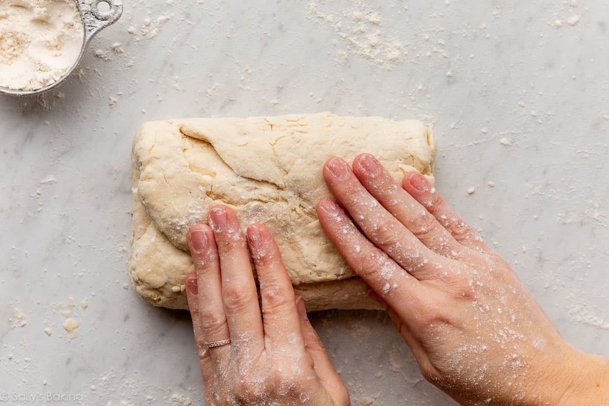 hands folding down dough.
