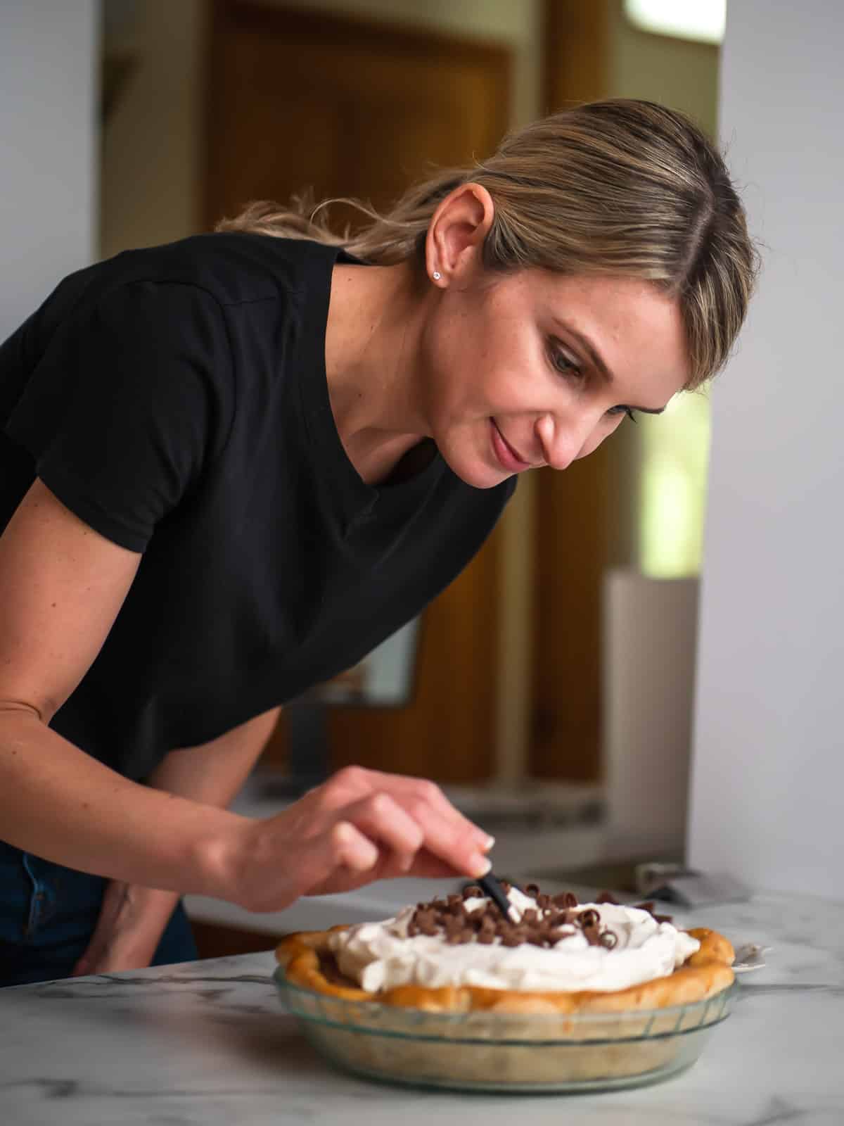 Sally applying chocolate curls to pie with tweezers.