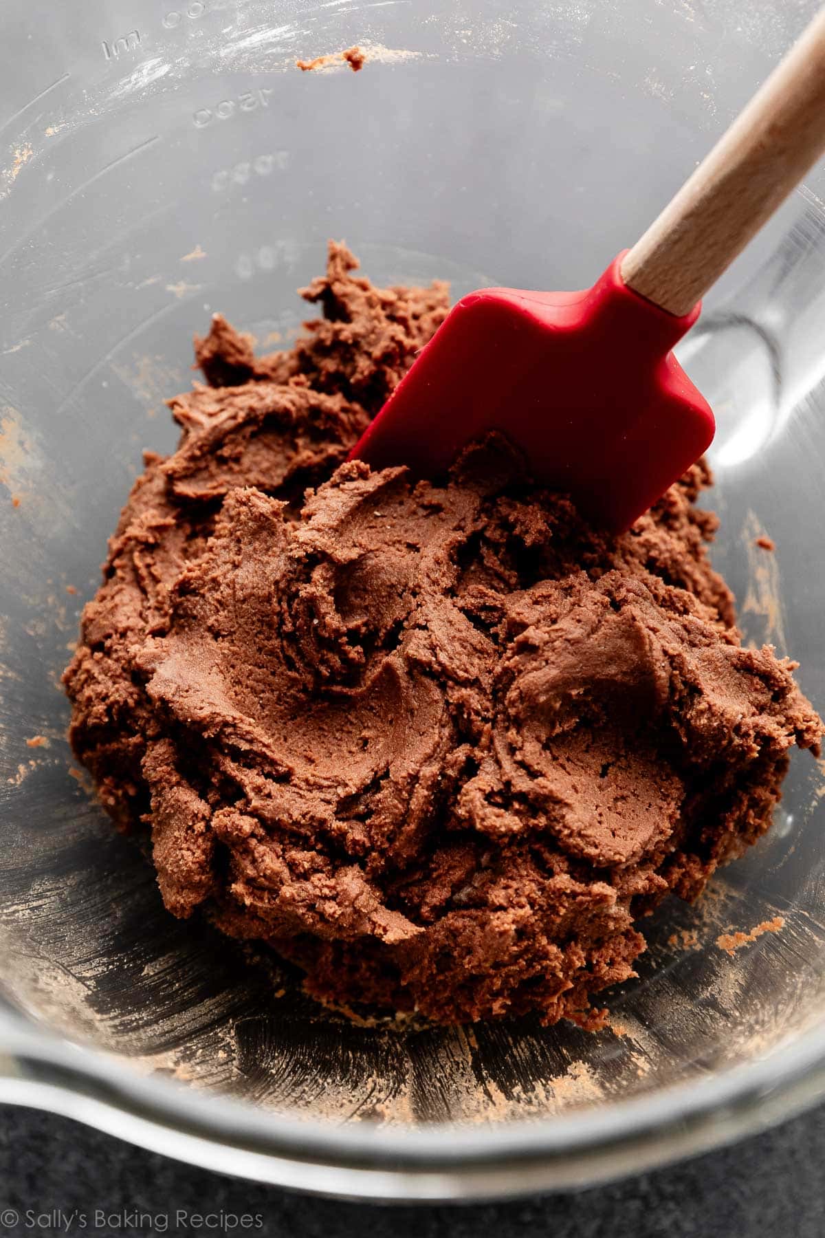 hot cocoa cookie dough in glass bowl with red spatula.