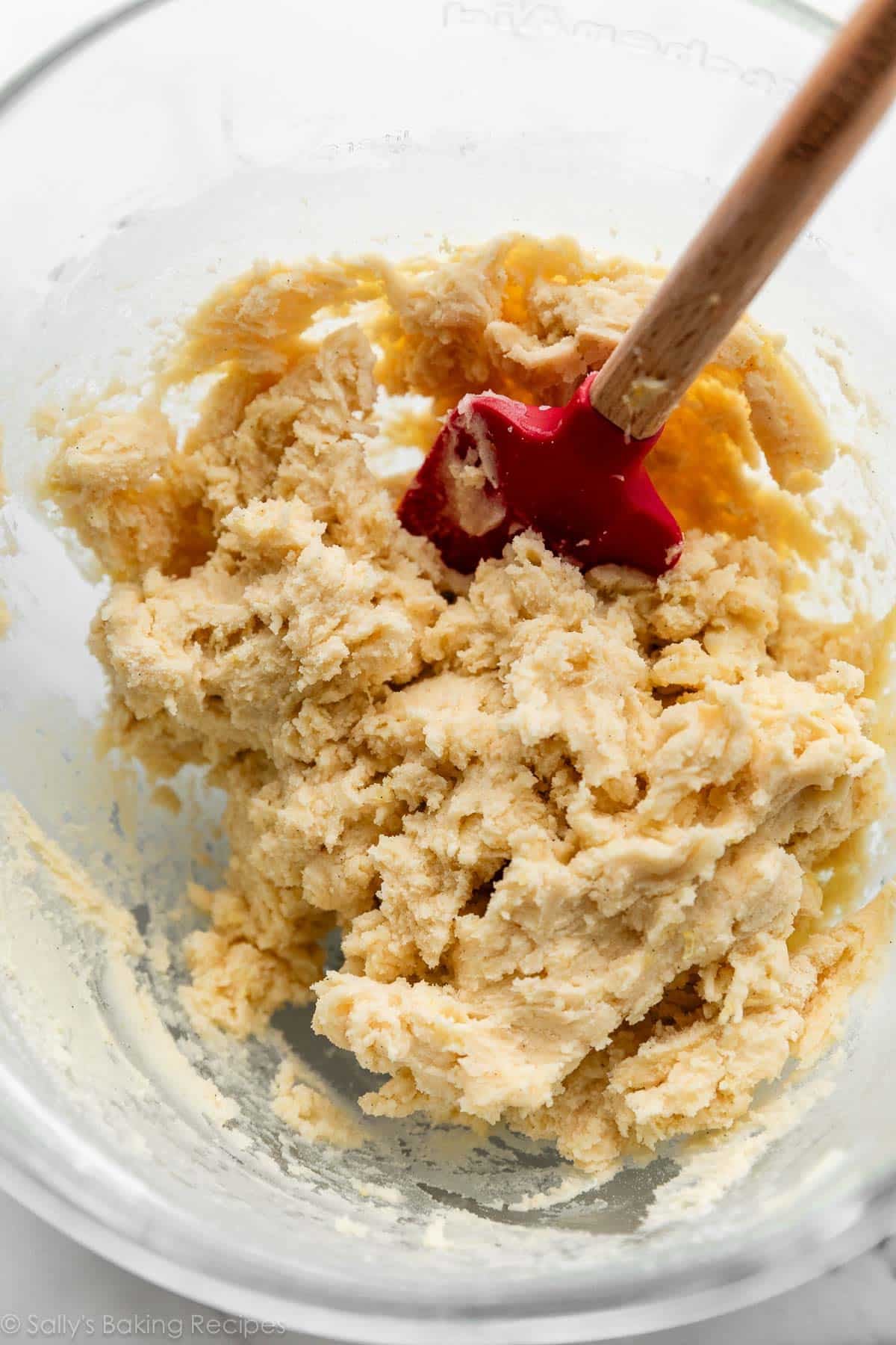 cookie dough in glass bowl with red spatula.