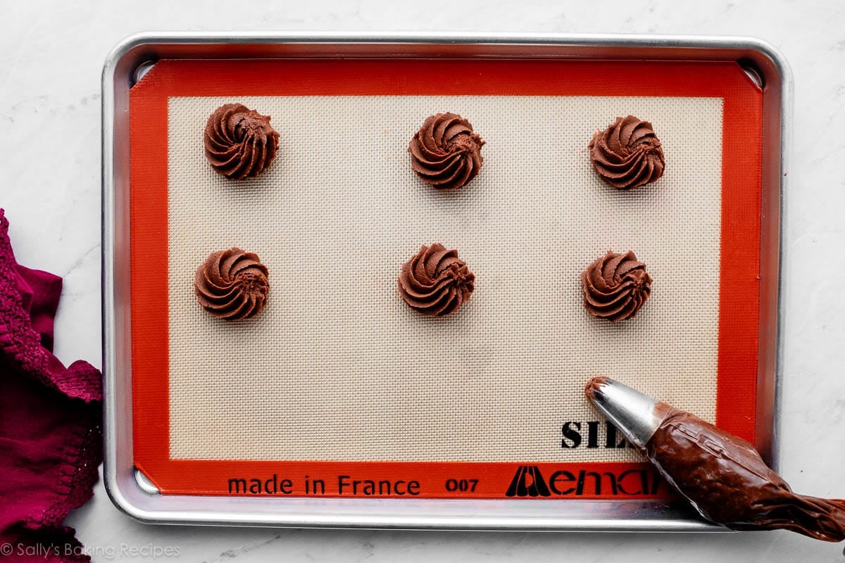 piping chocolate dough on lined baking sheet.