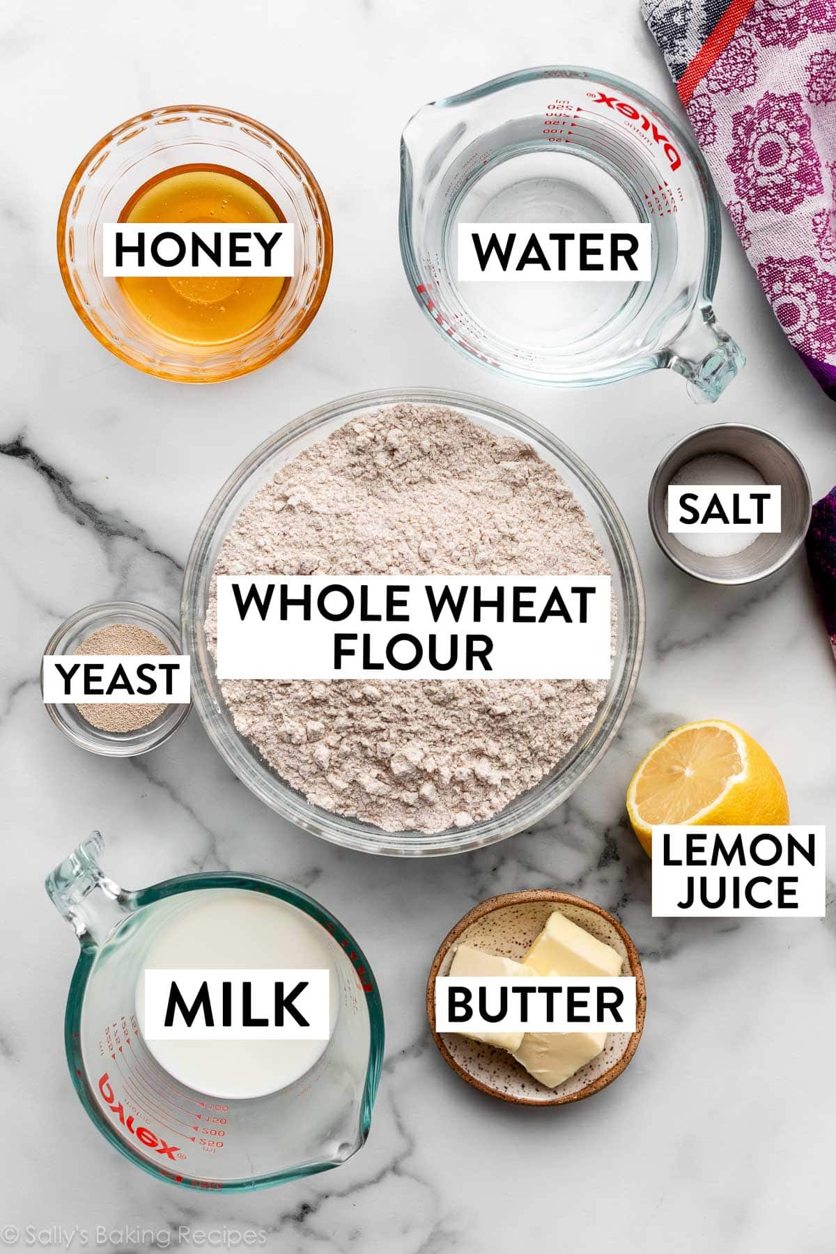 ingredients measured in bowls on counter including butter, milk, honey, flour, yeast, and salt.