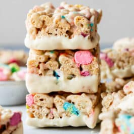 stack of 3 white chocolate dipped Lucky Charms cereal treats.