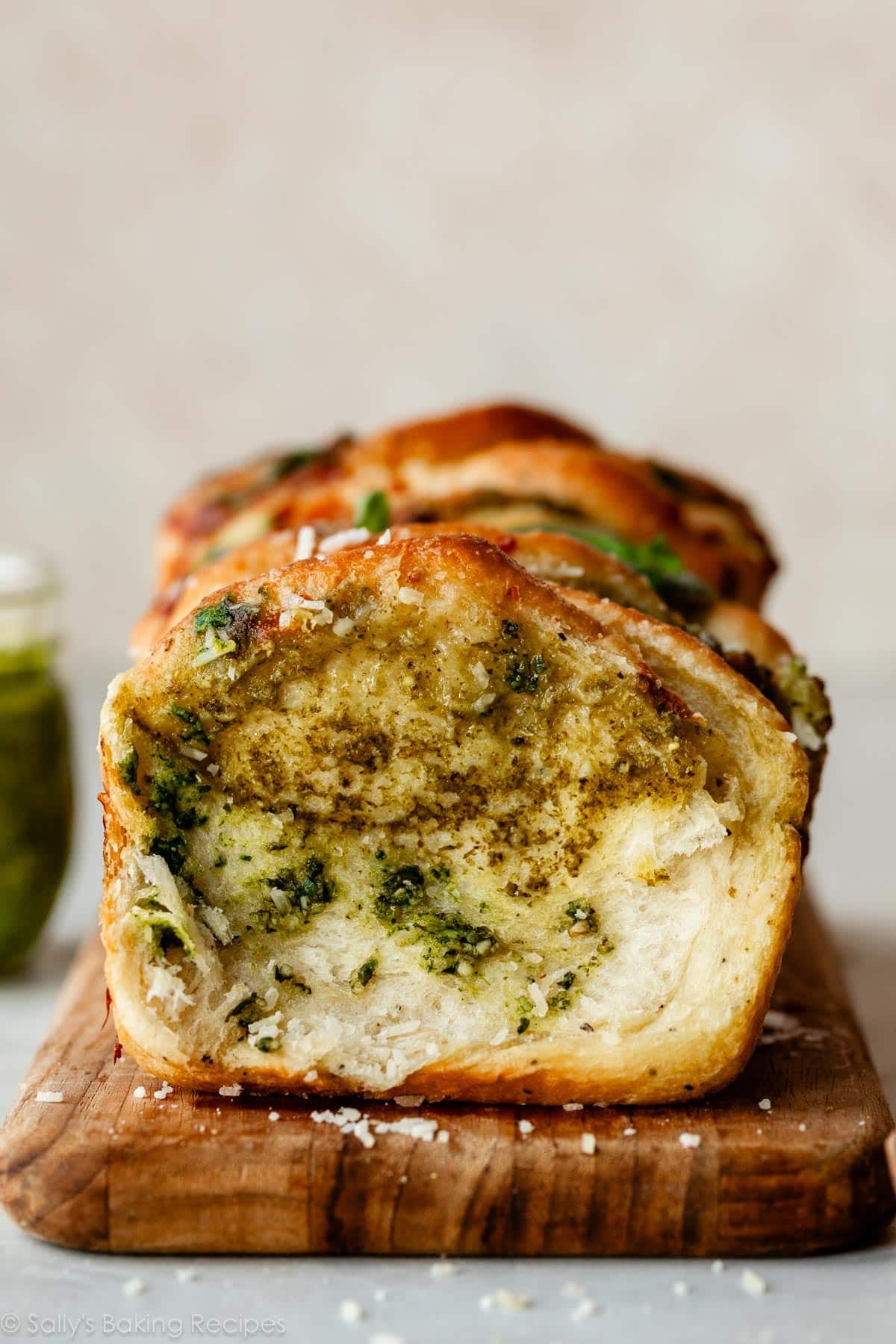 pesto pull apart bread on wooden cutting board.