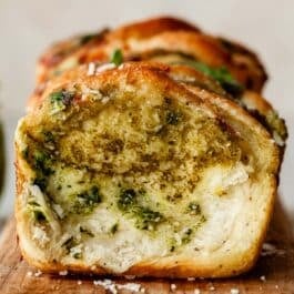 pesto pull apart bread on wooden cutting board.