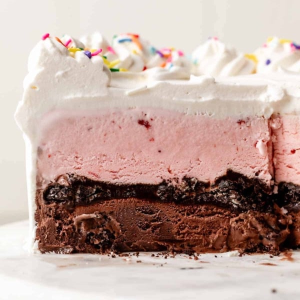 strawberry, Oreo crunch, and chocolate ice cream cake sliced on cake stand.