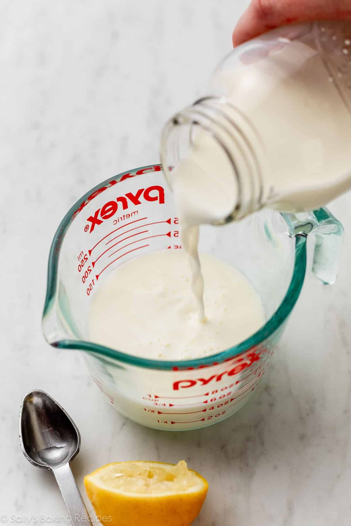 pouring milk into liquid measuring cup with lemon juice.