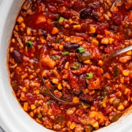 sweet potato chili with corn and kidney beans being spooned out with ladle.