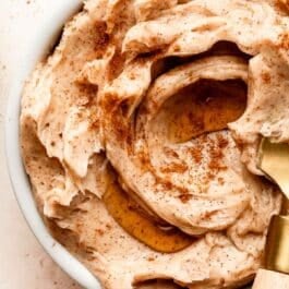 close-up of cinnamon butter in white dish with maple syrup drizzle on top.