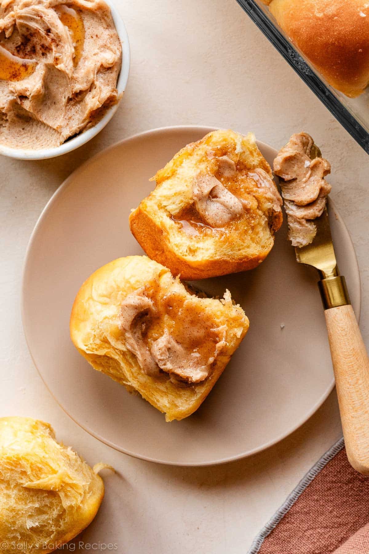 two sweet potato dinner rolls on beige plate.