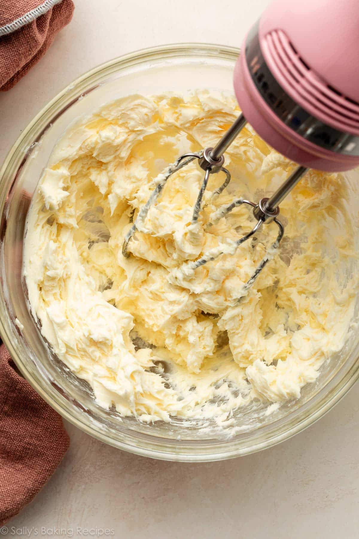 butter creamed in glass bowl with pink hand mixer.