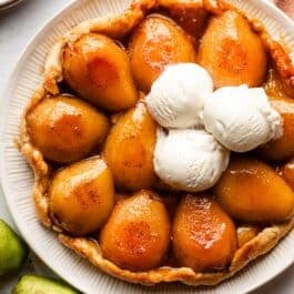 pear tarte tatin on a serving plate with 3 scoops of vanilla ice cream.