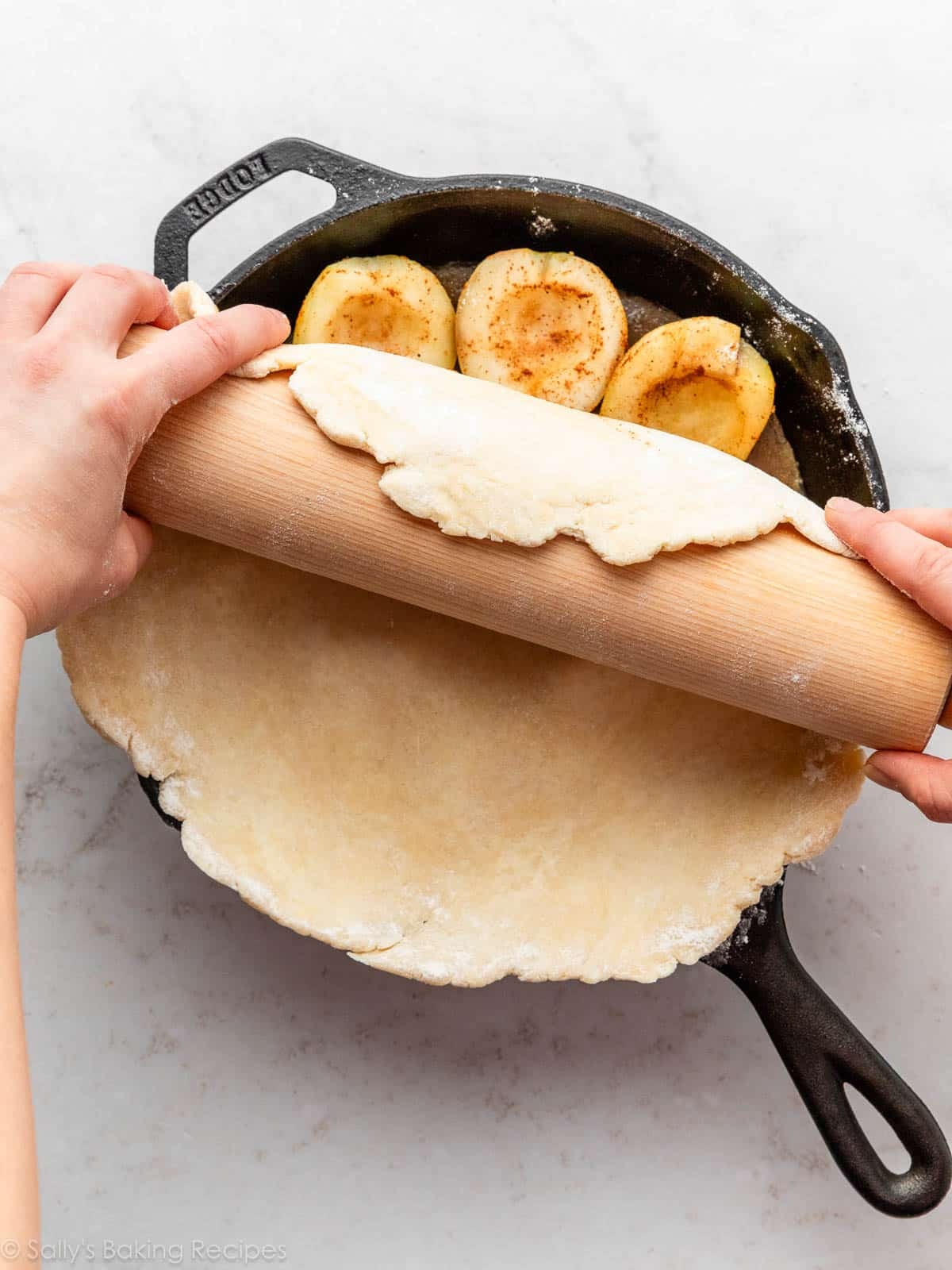 laying pastry dough over fruit in skillet.
