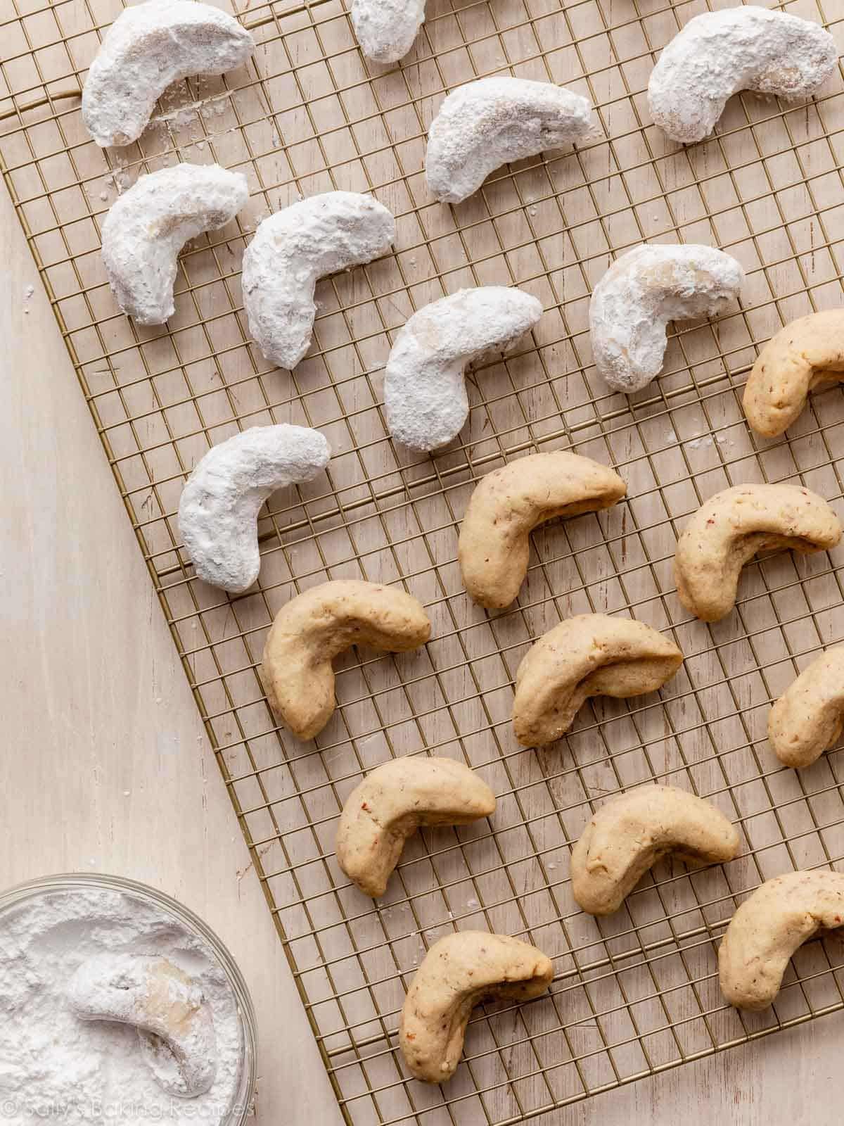 gold cooling rack with some crescent cookies on it and some are coated in powdered sugar.