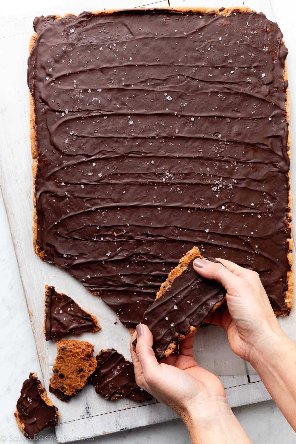 hands breaking cookie bark into pieces.