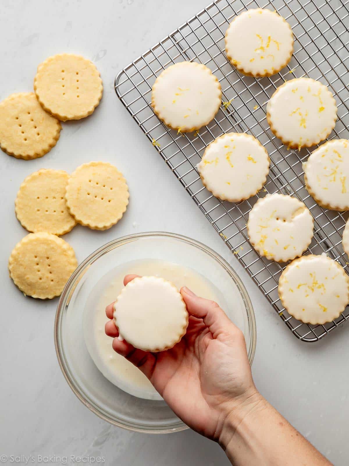 hand dipping shortbread cookies in icing.