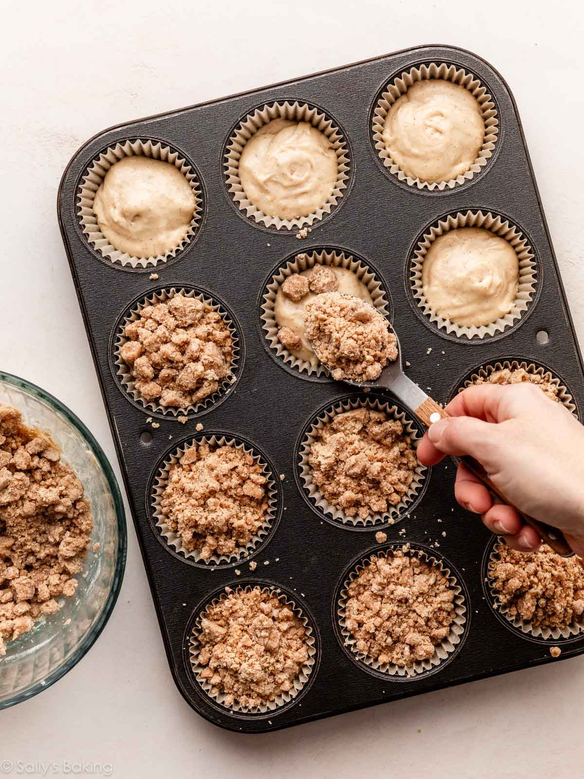 spooning crumbles on top of batter in a cupcake pan.