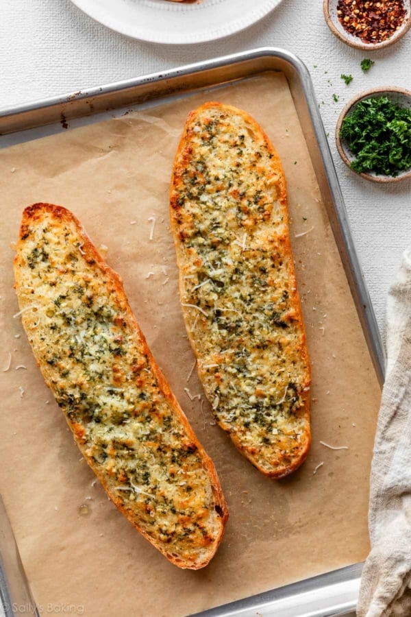 baked homemade garlic bread on parchment paper-lined baking sheet.