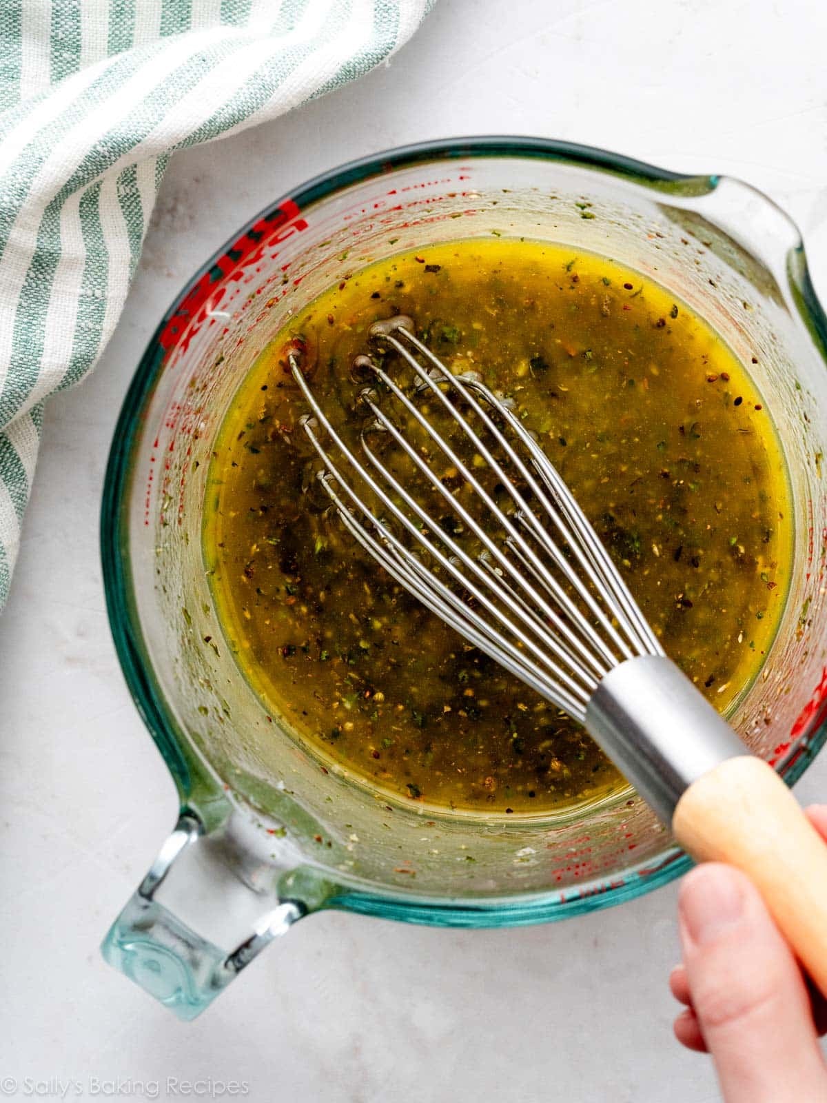 whisking olive oil mixture in large liquid measuring cup.