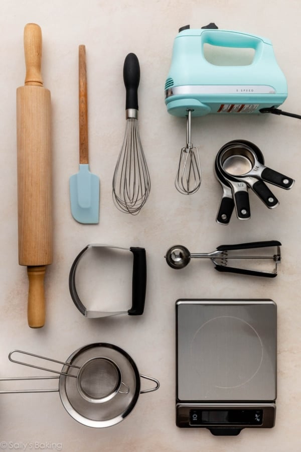 baking and kitchen tools laid out on beige surface.