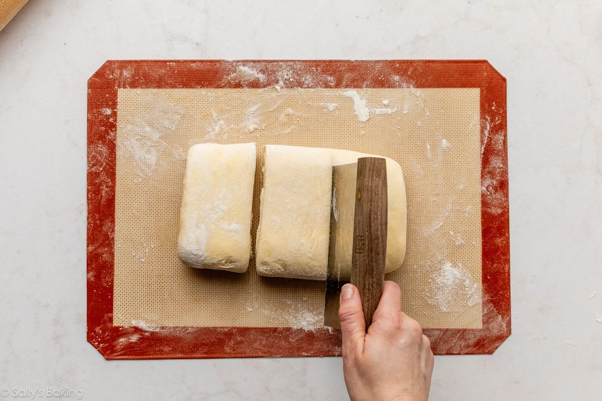 dough scraper cutting folded dough into 3 pieces.