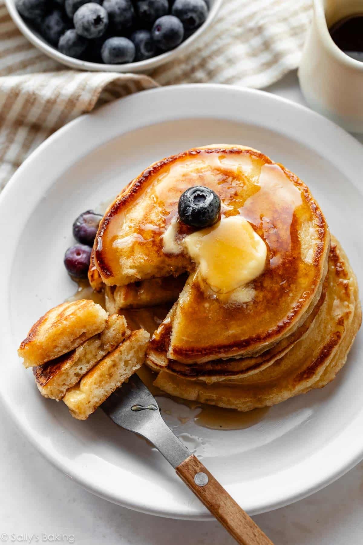 buttermilk pancakes on a white plate with a fork.