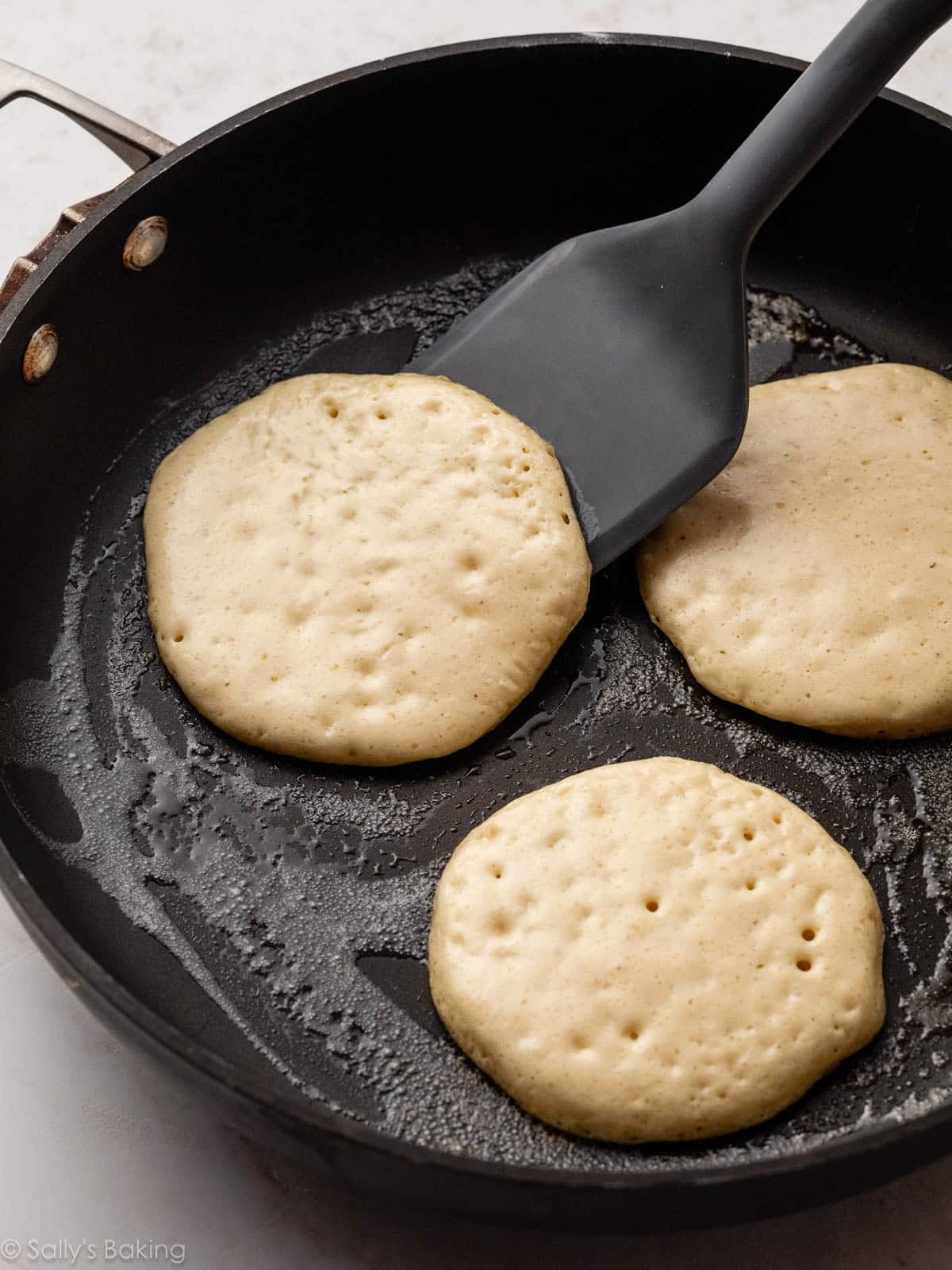 spatula flipping pancakes in skillet.