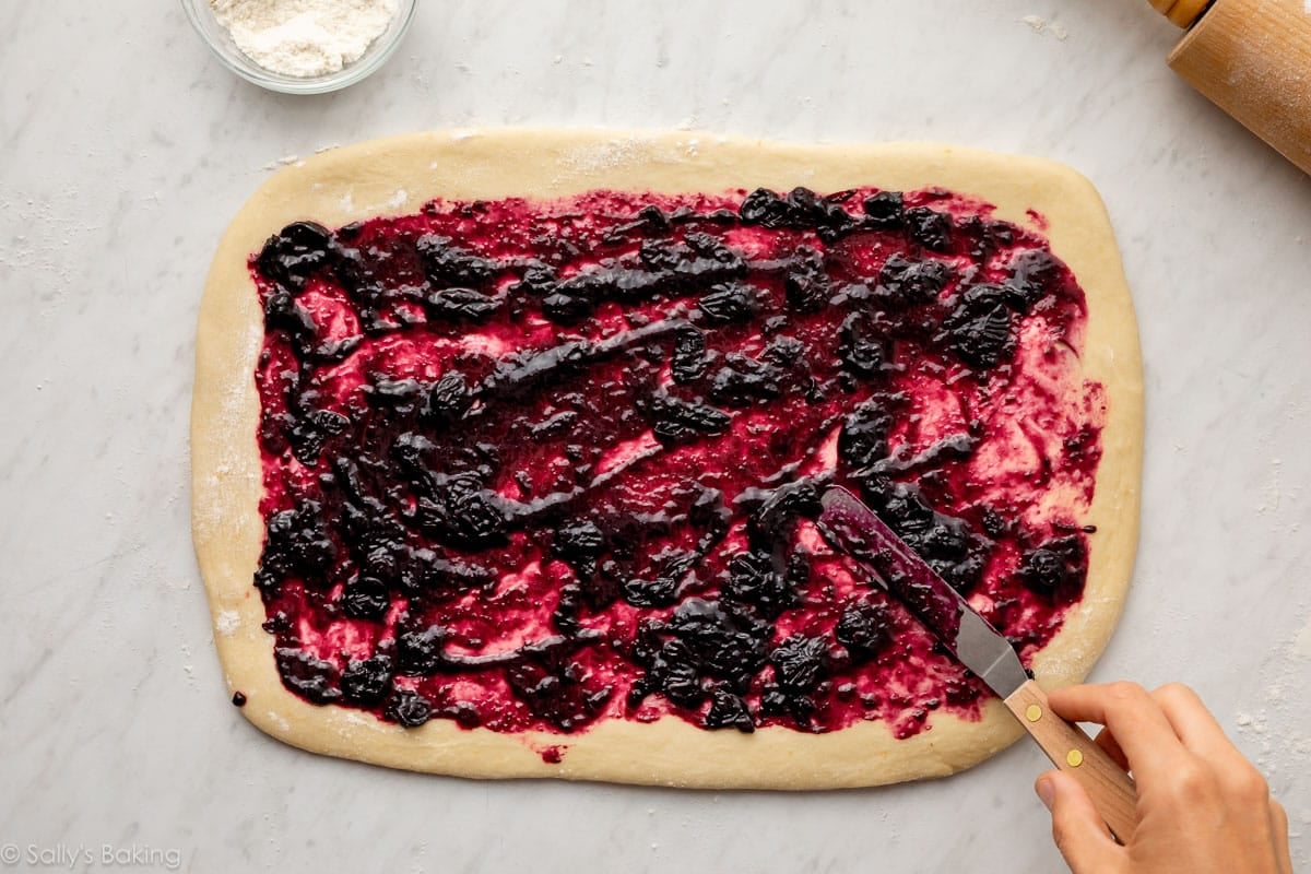 spreading blueberry filling rolled-out dough.