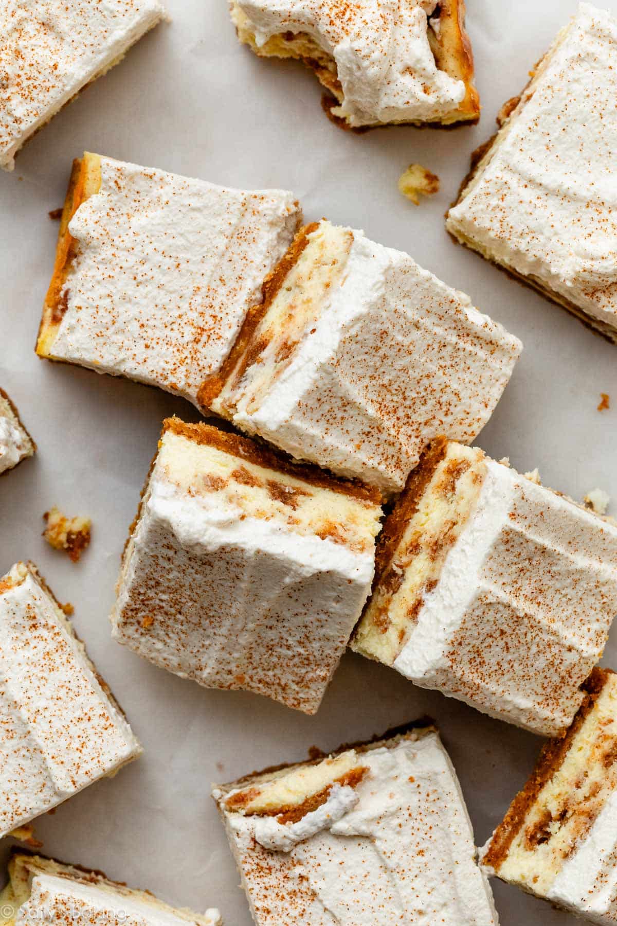 cinnamon roll cheesecake bars with whipped cream on top.