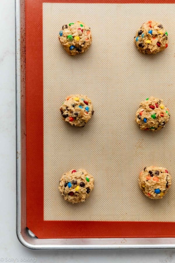 monster cookie dough balls on lined baking sheet.
