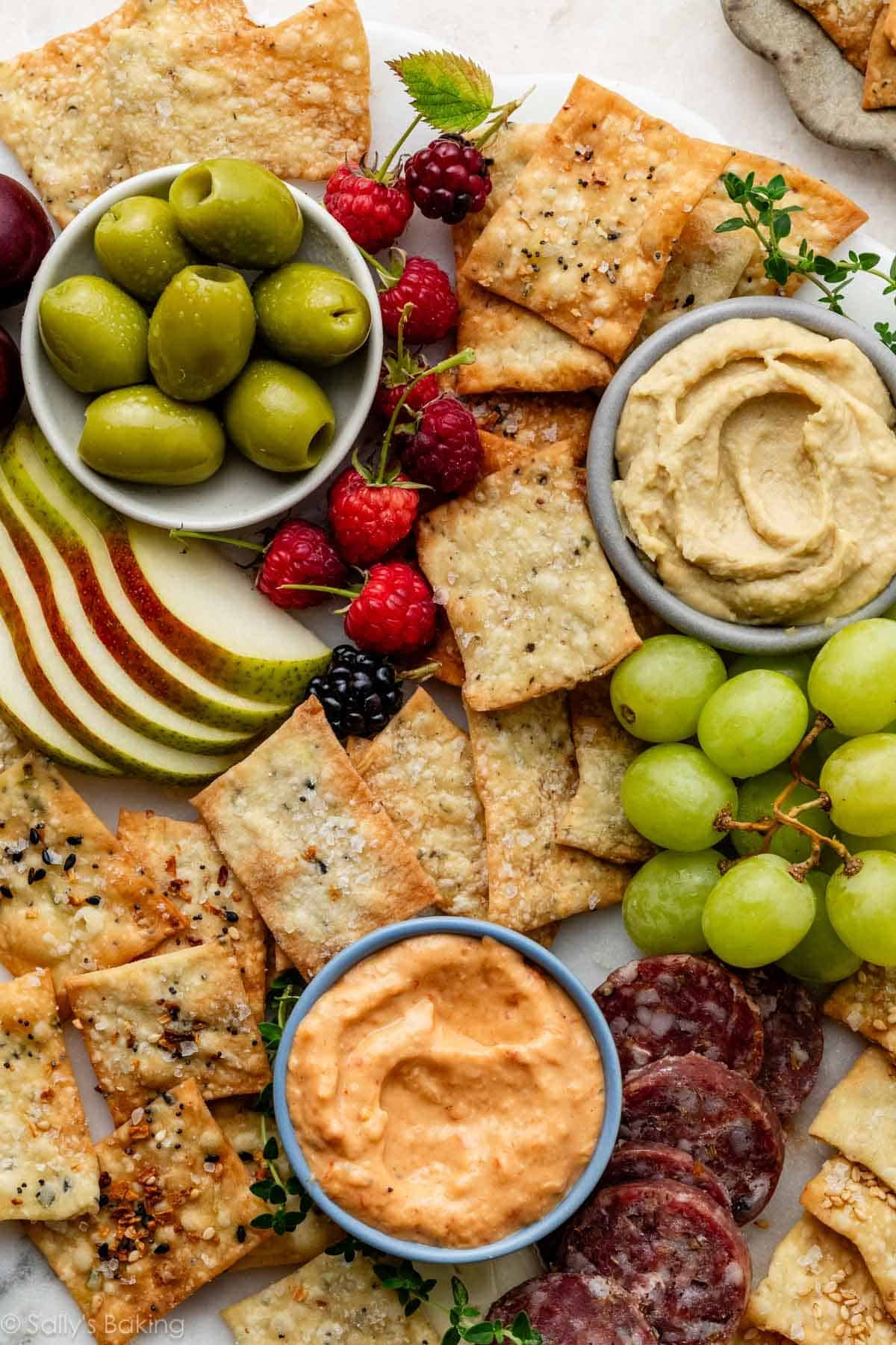 charcuterie platter with homemade crackers, olives, salami, grapes, and hummus.