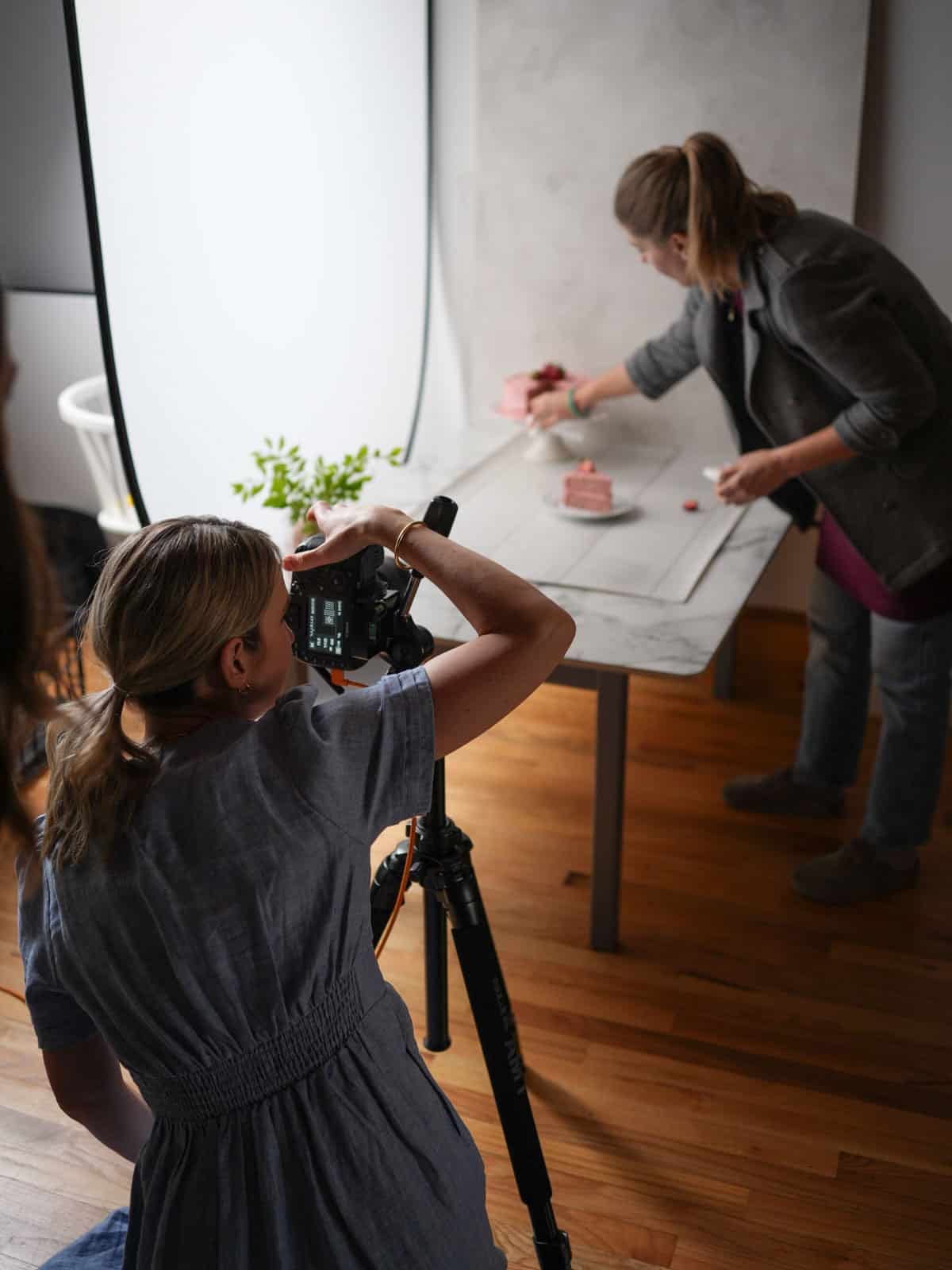 Sally taking photo with stylist of strawberry cake.