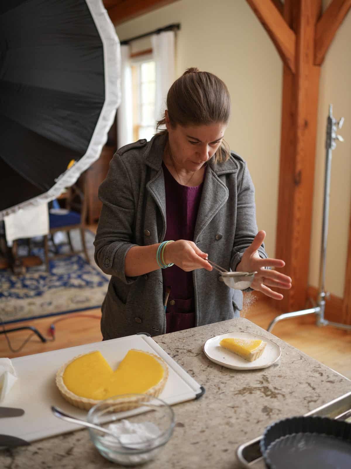 sprinkling sugar on lemon tart slice.