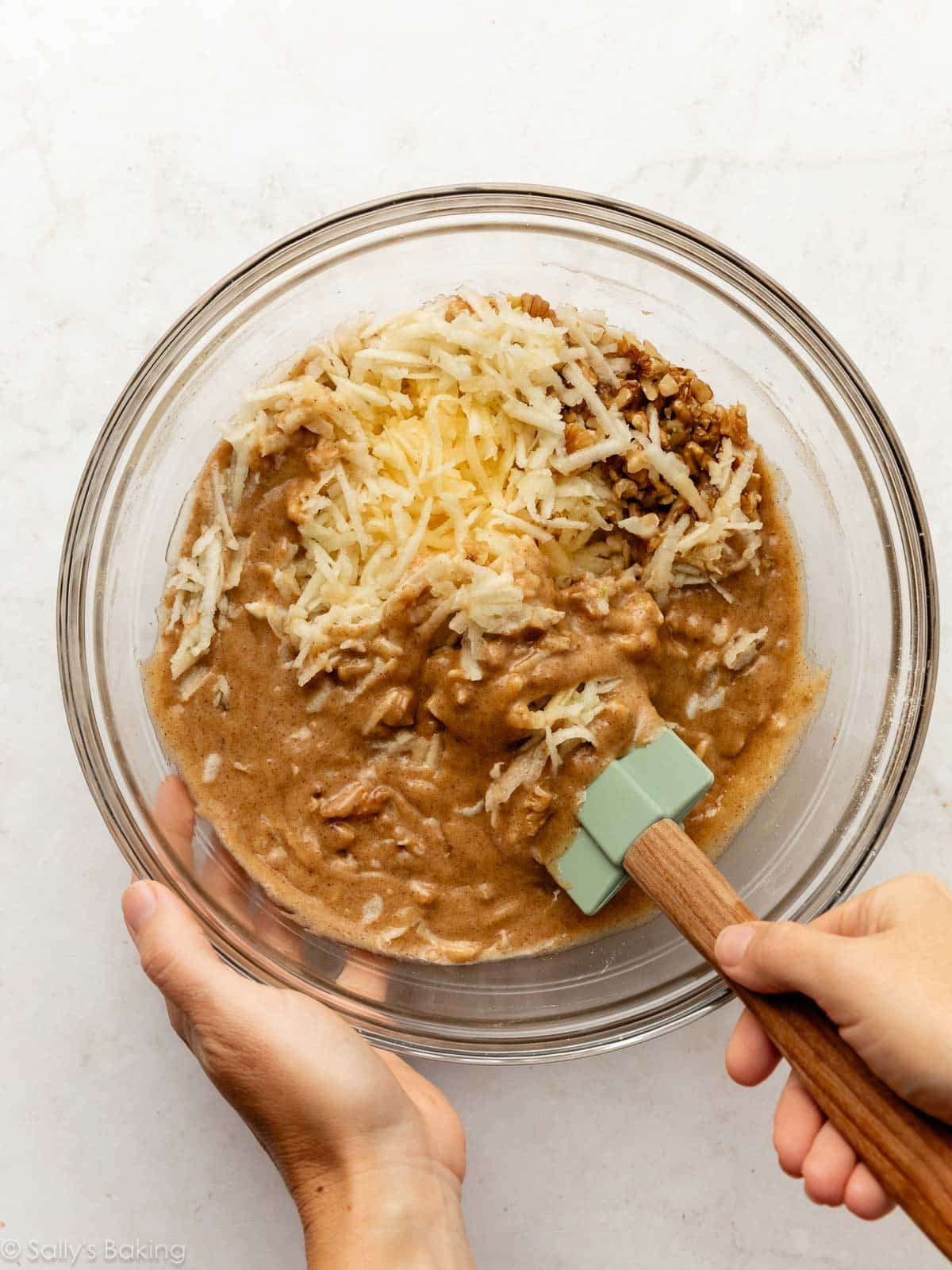 shredded apples and chopped walnuts in glass bowl with batter.
