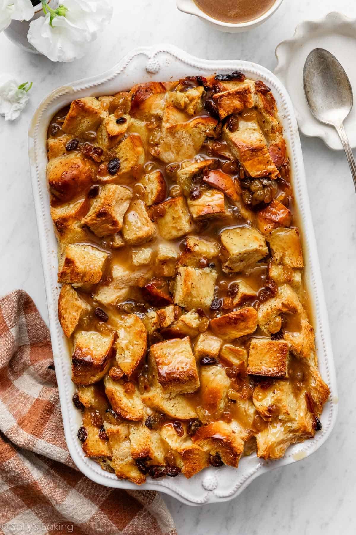 bread pudding in casserole dish with butter rum sauce and raisins.