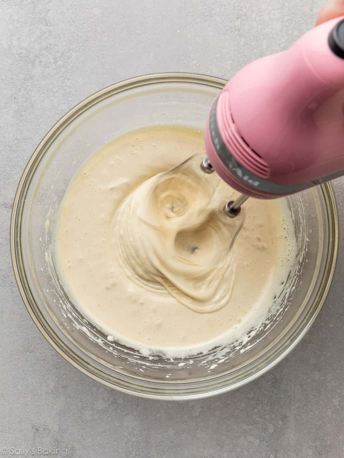 hand mixer beating eggs and sugar in glass bowl.
