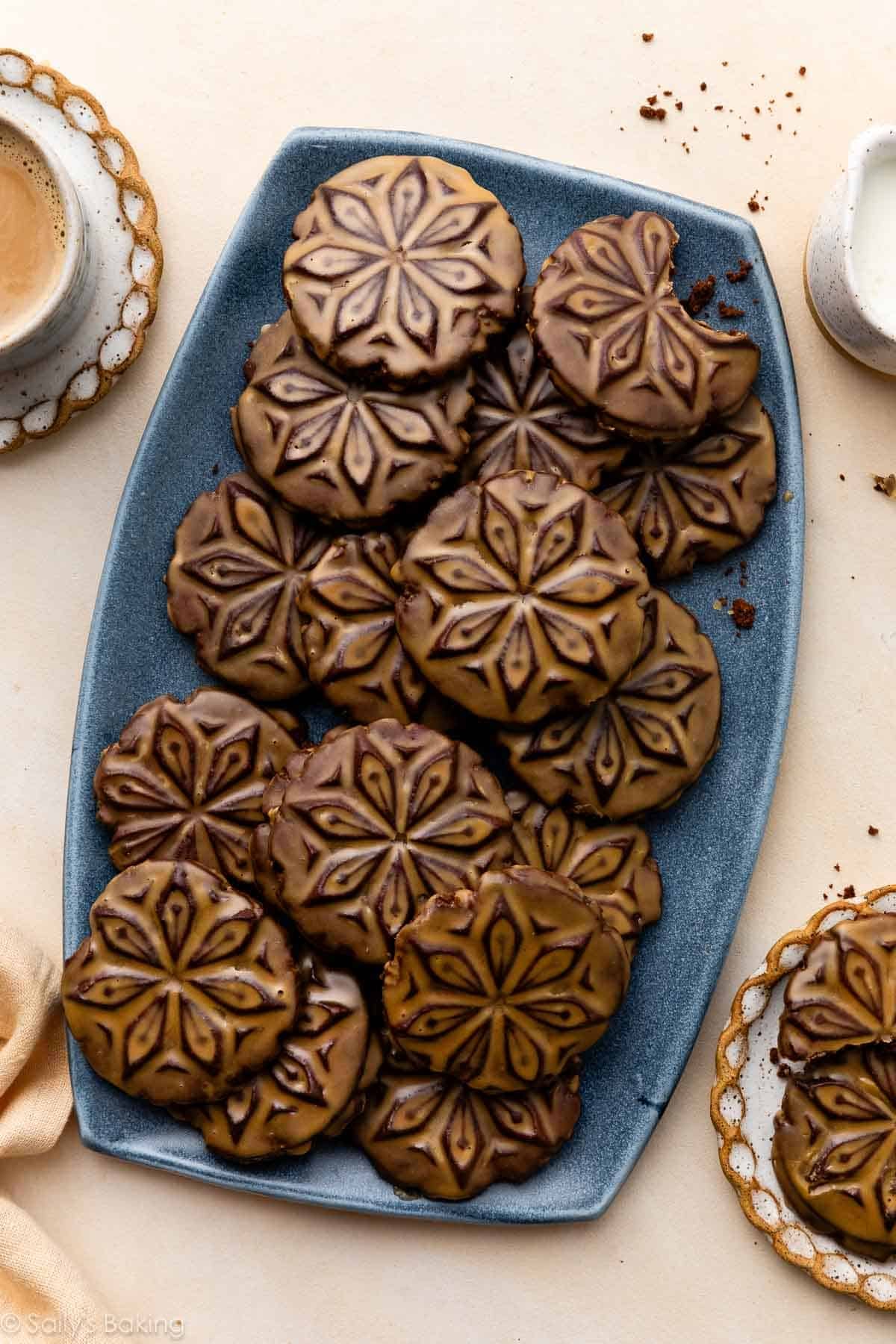 stamped chocolate cookies with espresso glaze on blue platter.