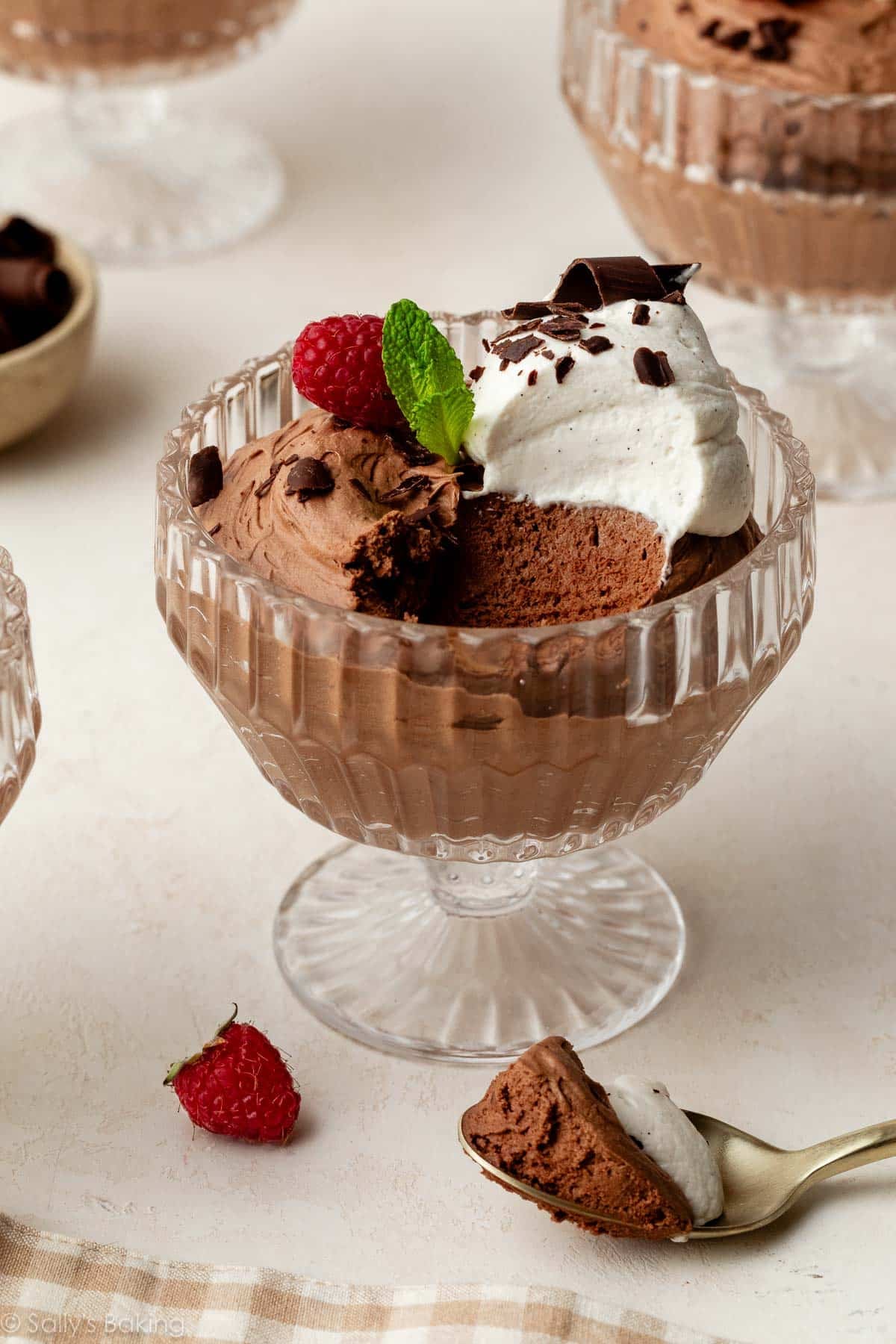 chocolate mousse in glass cup with whipped cream and raspberries.
